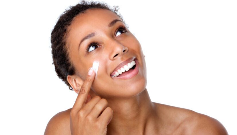 Smiling woman applying lotion on face